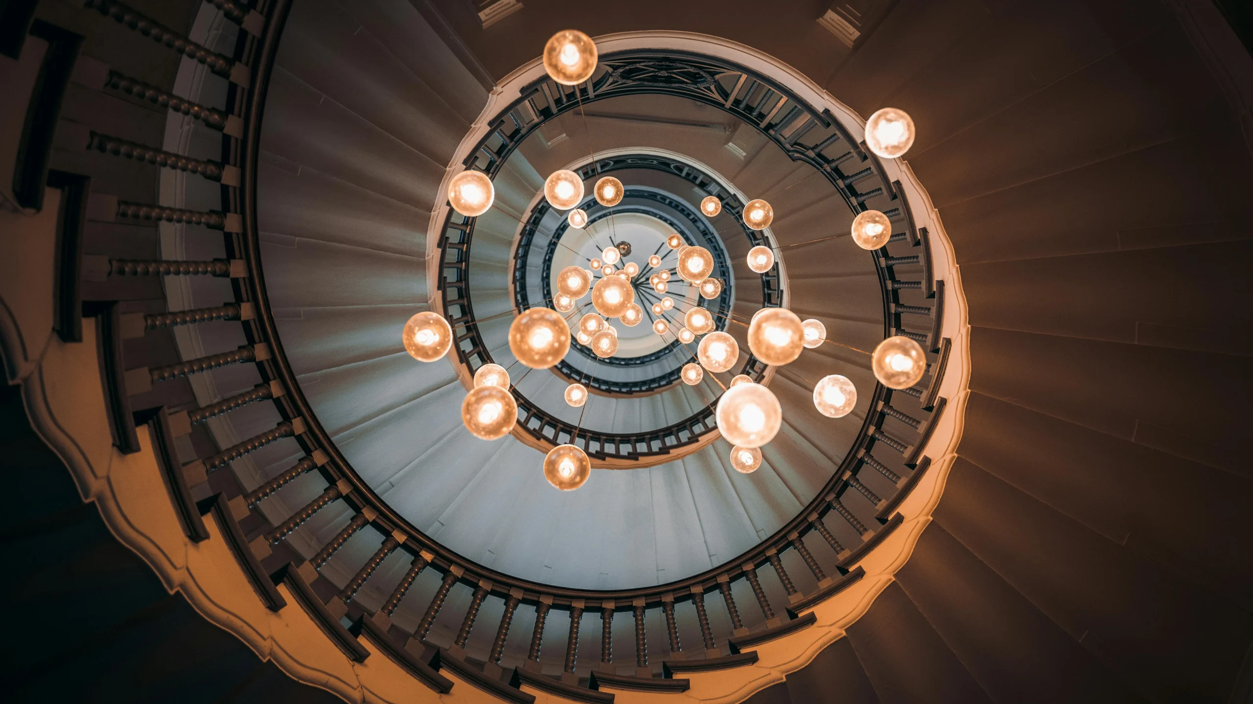 Elegant spiral staircase in London with a stunning chandelier, creating a mesmerizing visual effect.